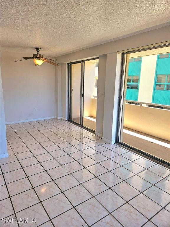 unfurnished room featuring ceiling fan, light tile patterned floors, and a textured ceiling