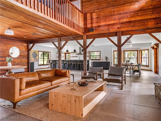 living room with a high ceiling, wood walls, and visible vents