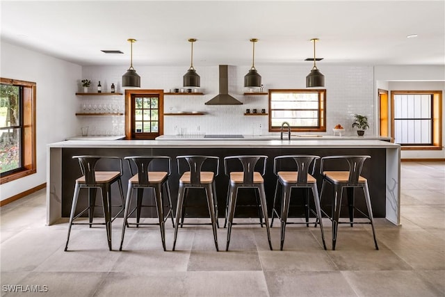 bar with a sink, visible vents, hanging light fixtures, wall chimney exhaust hood, and tasteful backsplash