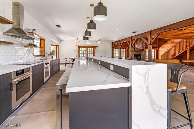 kitchen featuring french doors, wall chimney range hood, oven, decorative light fixtures, and decorative backsplash