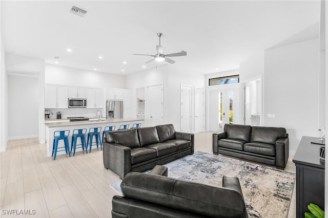 living room with ceiling fan, sink, and light hardwood / wood-style flooring