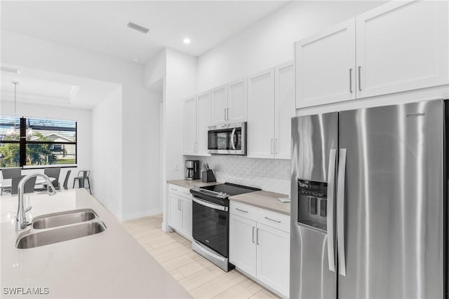 kitchen featuring white cabinetry, sink, pendant lighting, and appliances with stainless steel finishes