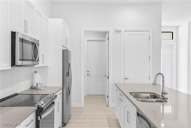 kitchen featuring light wood-type flooring, white cabinetry, sink, and appliances with stainless steel finishes