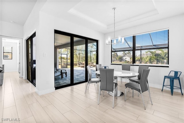 dining room with plenty of natural light, a chandelier, and a tray ceiling