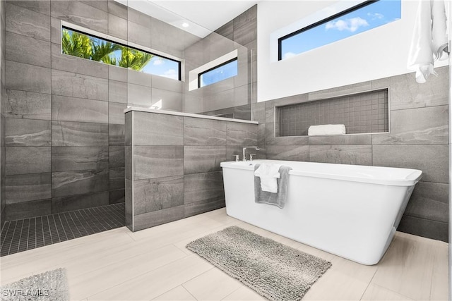 bathroom with separate shower and tub, tile patterned floors, a wealth of natural light, and tile walls