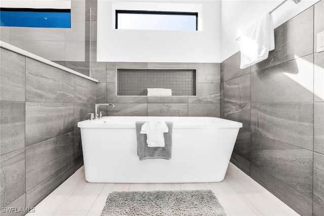 bathroom with a bathing tub and tile walls