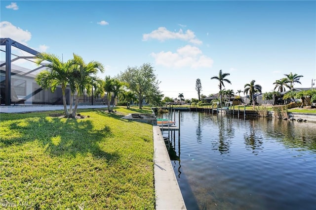 dock area with a yard, a water view, and glass enclosure