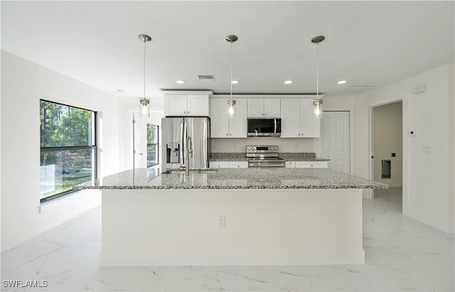 kitchen with decorative light fixtures, white cabinetry, a large island with sink, and appliances with stainless steel finishes