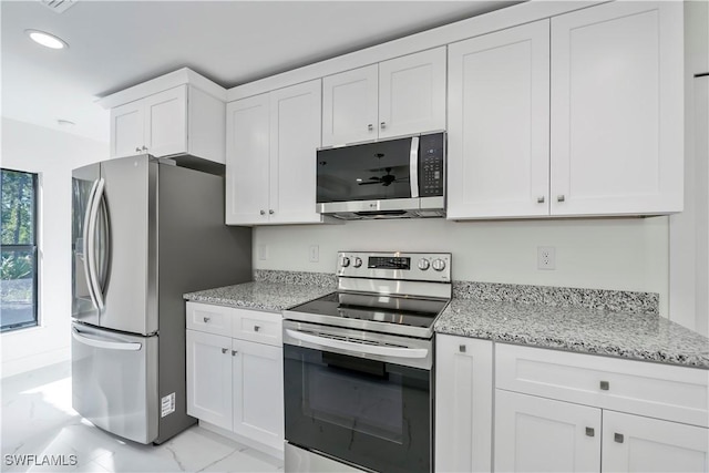 kitchen with light stone countertops, white cabinetry, and appliances with stainless steel finishes