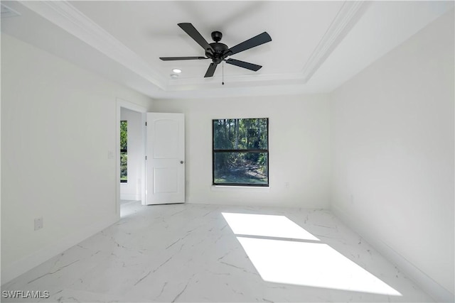 empty room with ceiling fan, a raised ceiling, and crown molding