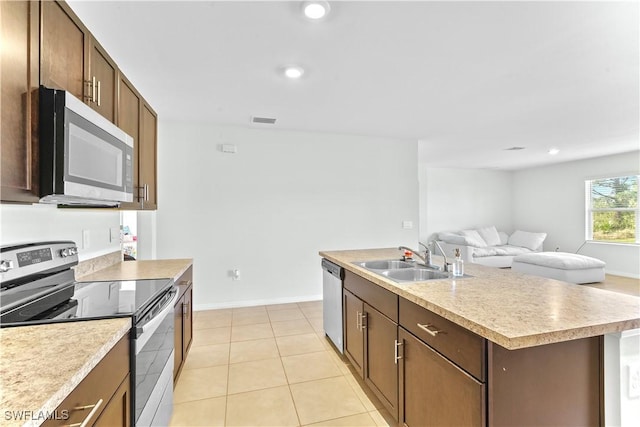 kitchen with a kitchen island with sink, sink, light tile patterned flooring, and appliances with stainless steel finishes