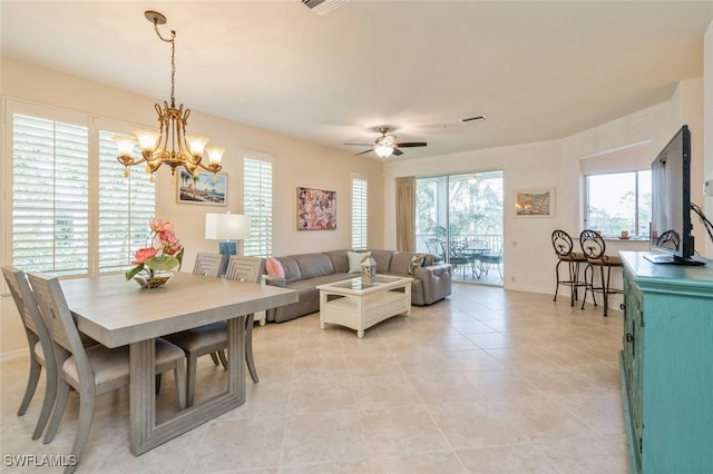 tiled dining space featuring ceiling fan with notable chandelier and a healthy amount of sunlight