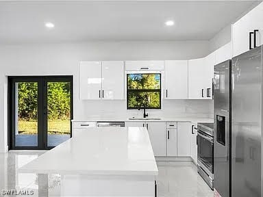 kitchen featuring french doors, sink, a center island, appliances with stainless steel finishes, and white cabinets