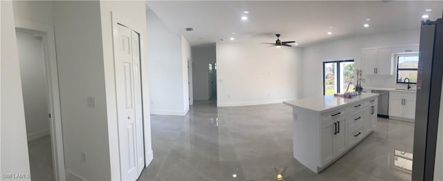 kitchen featuring sink, a center island, ceiling fan, stainless steel appliances, and white cabinets