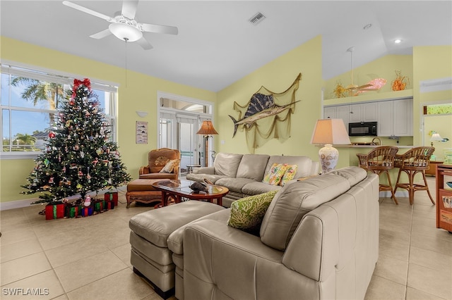 living room with ceiling fan, lofted ceiling, and light tile patterned flooring