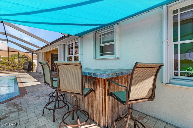 view of patio with exterior bar and a lanai