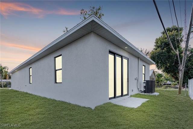 property exterior at dusk with a lawn and cooling unit