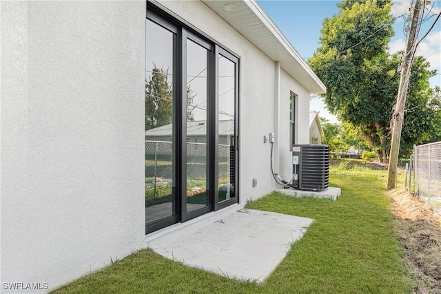 exterior space featuring a lawn, a patio area, and central air condition unit