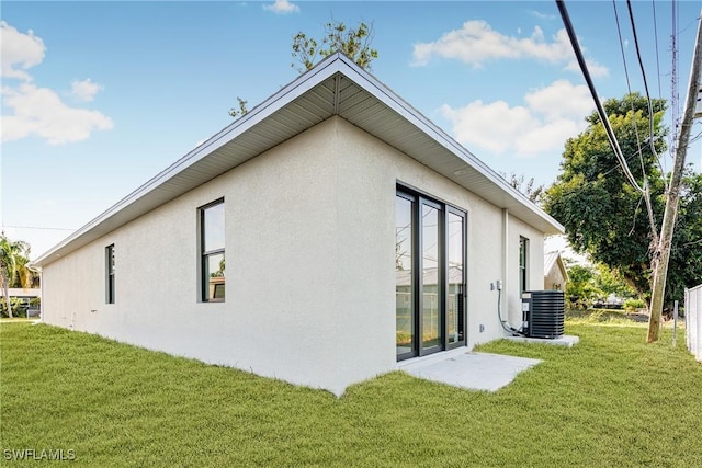 view of side of home with a yard and central AC unit