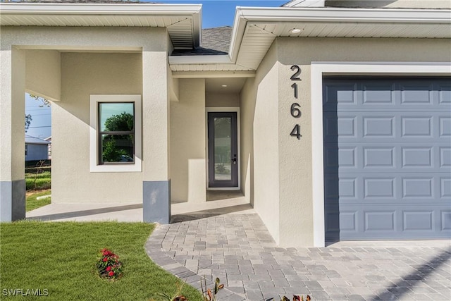 entrance to property featuring a garage and a lawn