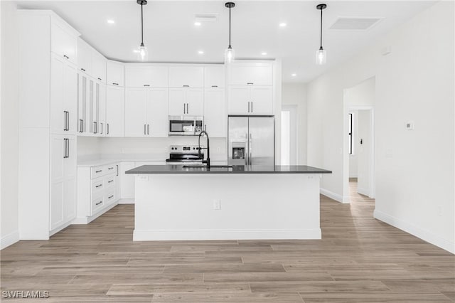 kitchen featuring a center island with sink, white cabinets, sink, decorative light fixtures, and stainless steel appliances