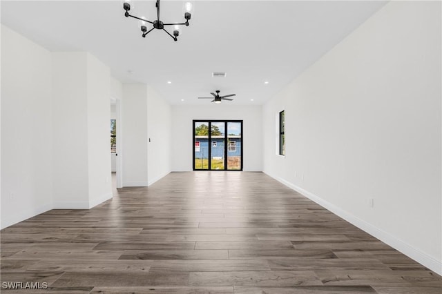 unfurnished room featuring ceiling fan with notable chandelier and dark hardwood / wood-style floors