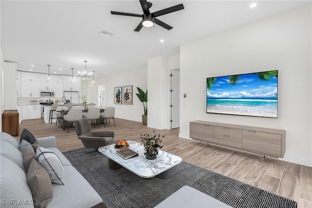 living room featuring light hardwood / wood-style floors and ceiling fan with notable chandelier