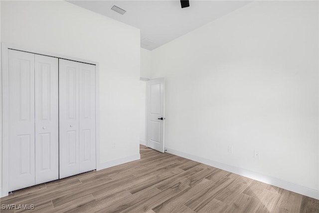 unfurnished bedroom featuring a closet, light hardwood / wood-style flooring, and ceiling fan