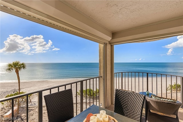 balcony featuring a beach view and a water view