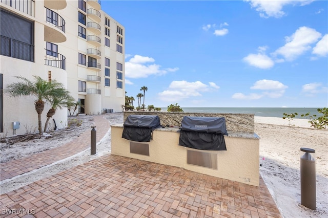 view of patio featuring a grill, a water view, and a view of the beach