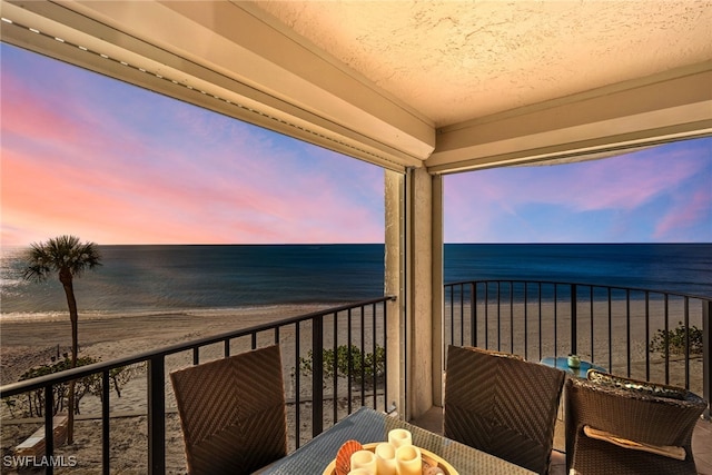 balcony at dusk with a beach view and a water view