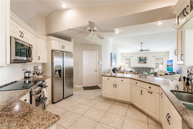 kitchen featuring light stone counters, stainless steel appliances, and lofted ceiling