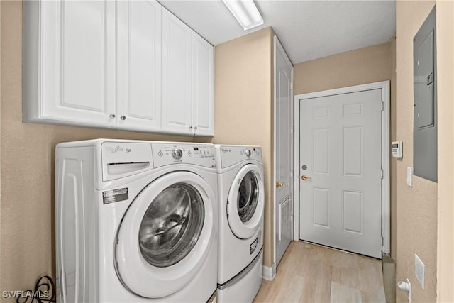 laundry area featuring cabinets, washer and clothes dryer, and light hardwood / wood-style floors