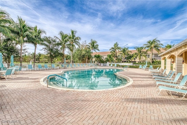 community pool with a patio area and fence