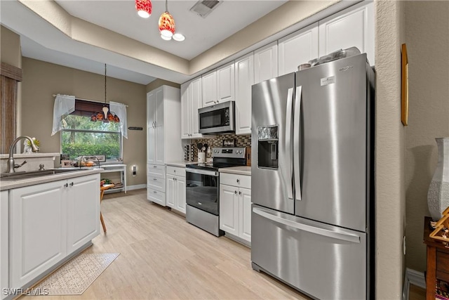 kitchen with tasteful backsplash, visible vents, hanging light fixtures, appliances with stainless steel finishes, and white cabinets