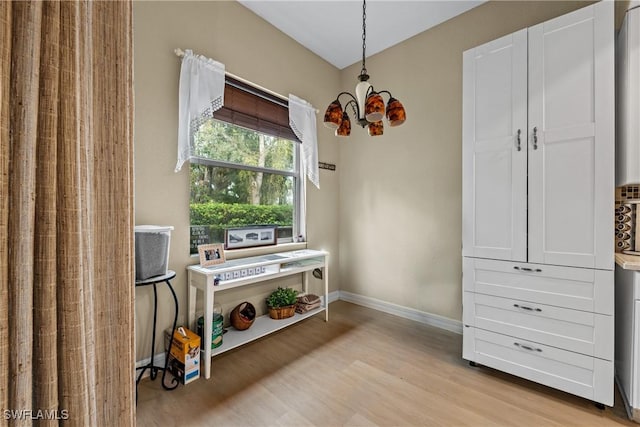 miscellaneous room featuring a chandelier and light wood-type flooring