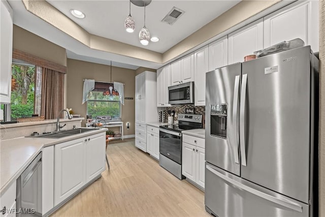 kitchen featuring sink, decorative light fixtures, light hardwood / wood-style floors, white cabinetry, and stainless steel appliances