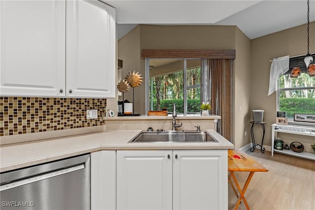 kitchen with light countertops, backsplash, white cabinetry, a sink, and dishwasher