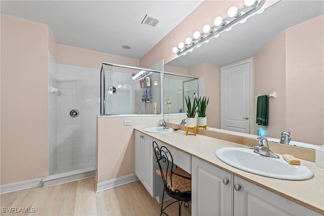 full bath featuring visible vents, a walk in shower, a sink, and wood finished floors