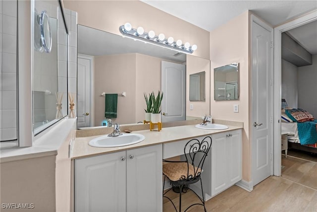 ensuite bathroom with double vanity, wood finished floors, a sink, and ensuite bathroom