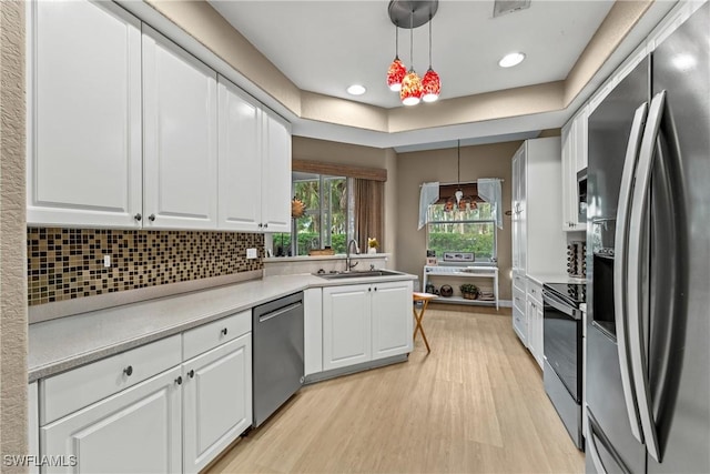 kitchen featuring decorative light fixtures, sink, white cabinetry, and stainless steel appliances