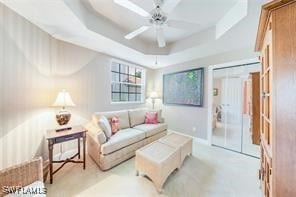 living room featuring a raised ceiling and ceiling fan