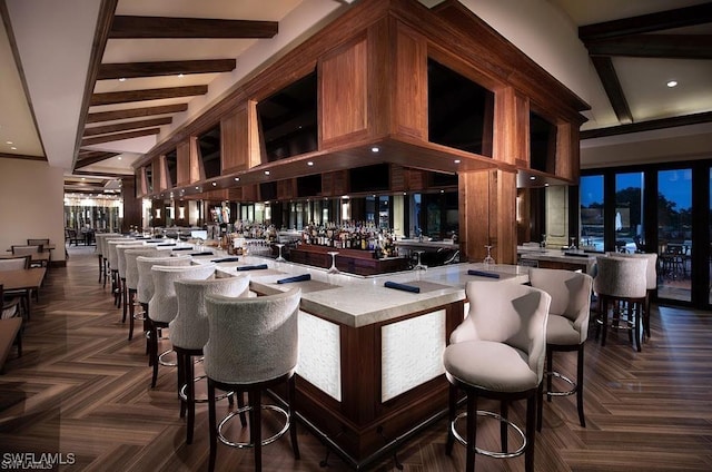 bar with a high ceiling, indoor wet bar, and beamed ceiling