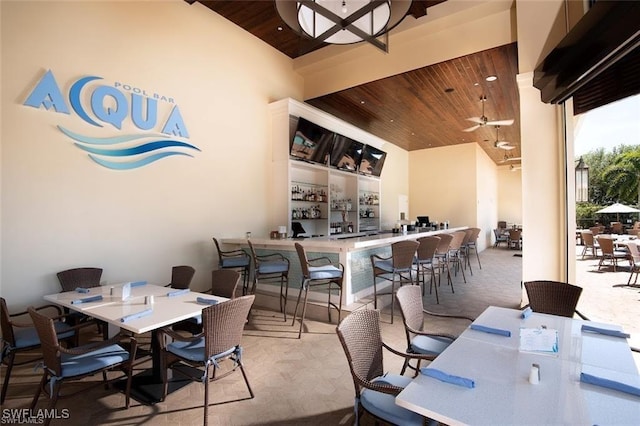 dining space featuring a towering ceiling, wood ceiling, carpet floors, and a ceiling fan