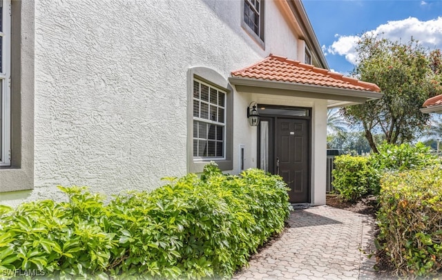 property entrance with a tiled roof and stucco siding