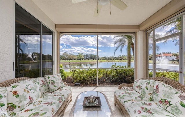 sunroom featuring ceiling fan and a water view