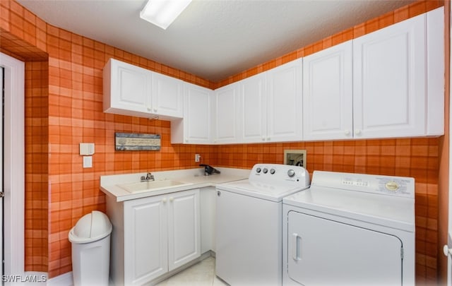 washroom with cabinet space, a sink, and washing machine and clothes dryer