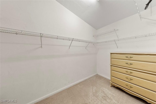 spacious closet with light colored carpet and lofted ceiling