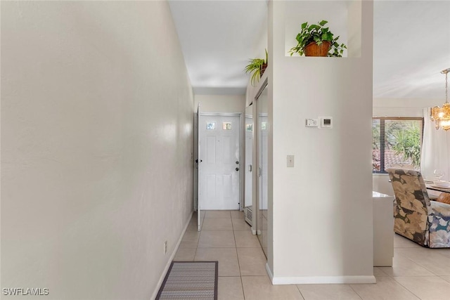 hall with light tile patterned floors and a notable chandelier