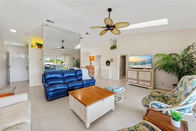 tiled living room featuring ceiling fan and vaulted ceiling with skylight